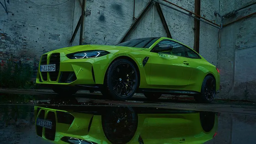 BMW M4 garée devant un bâtiment moderne, vue latérale